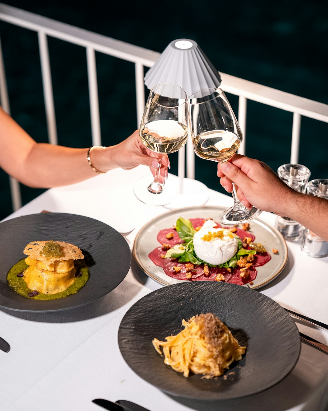 couple-toasting-with-wine-over-a-dinner-spread-kkkdzfadwom